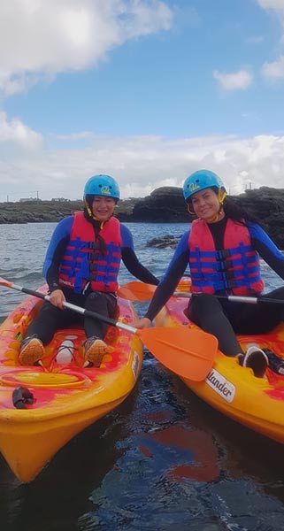 Two ladies pose for a picture while out sea kayaking on Anglesey